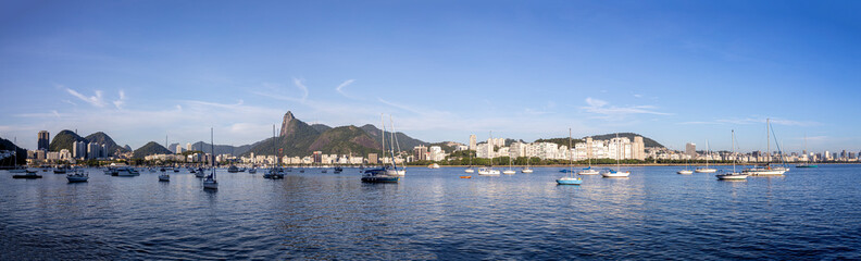 Wide panorama view of Rio de Janeiro at sunrise with the Corcovado mountain in the background and pleasure boats scattered in the Guanabara bay in front seen from the Urca neighbourhood