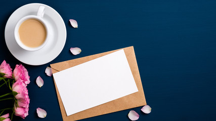 Obraz na płótnie Canvas Valentine day greeting card mockup on envelope, coffee cup, roses flowers, petals over blue background. Flat lay, top view. Love, romantic letter concept.