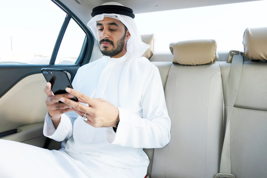 Emirati Arab man on duty wearing traditional Kandura. Arabic national using electronic devices ideal for internet browsing, online banking, ecommerce or mobile app mock up