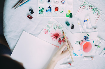 Beautiful girl artist paints with watercolors in a bright studio. Art. Drawing