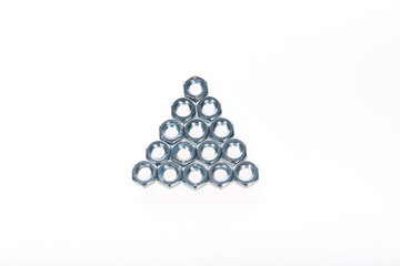 Metal nuts laid out in the form of a triangle on a white background