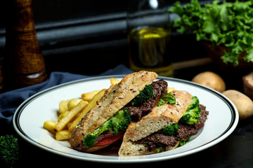 beef sandwich with broccoli, tomato in bread served with fries