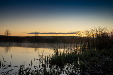 Vivid orange sunset reflected in a tranquil lake