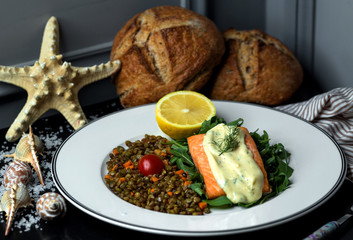 fried salmon fillet garnished with sauce, served with roasted lentil and carrot