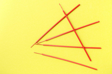 Incense aroma sticks red color scattered on a yellow background. Top view, copy space