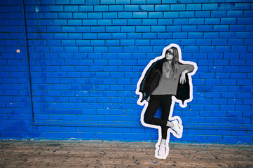 Collage in magazine style of fashionable woman in stylish clothes posing over blue brick wall on background.  Psychedelic woman portrait.