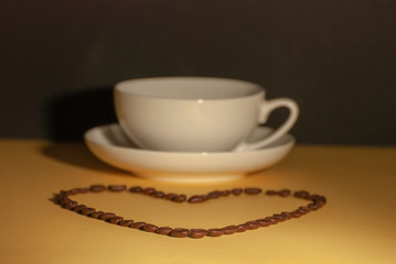 heart shape made from coffee beans in front of a coffee cup