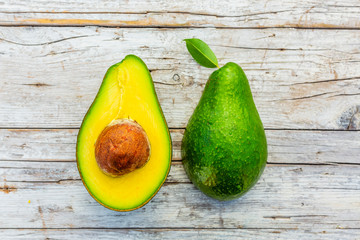 Ripe halves of avocado on a wooden background.