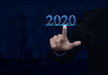 Businessman pressing 2020 text over world map, modern city tower and skyscraper, Happy new year 2020 calendar cover concept, Elements of this image furnished by NASA