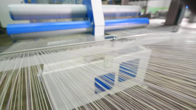 White strings moving on a factory machine while spooling. Industrial Textiles Production Line