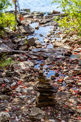 Pebbles, stacked stones as stone statues on the Muskoka river bay, Ontario, short depth of field, forest on background.