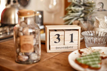New Year's interior. "December 31 " text wooden calendar, plate with tangerine and gingerbread. Christmas decoration, table in the kitchen. Stylish interior