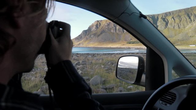 Tourist taking picture out of a car from a bay in Unstad, Lofoten, Norway
