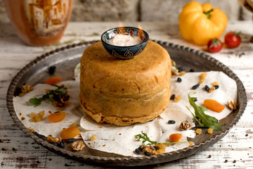 azerbaijani pilaf in crusty dough, served in antique tray with dried fruits and arugula
