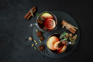 Two cups of Christmas mulled wine or punch with spices and lemon slices on dark wooden background. Christmas or New Year celebration concept