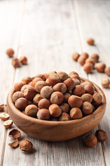 Hazelnuts in bowl on white wooden background. Selective focus.