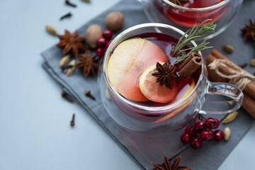 Two cups of Christmas mulled wine or punch with spices and lemon slices on gray wooden background....