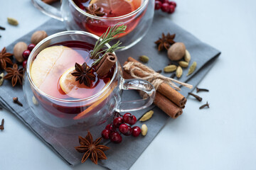 Two cups of Christmas mulled wine or punch with spices and lemon slices on gray wooden background....