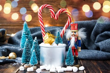 Christmas marshmallows, nutcracker and new year decorations on wood with grey plaid. Winter holidays