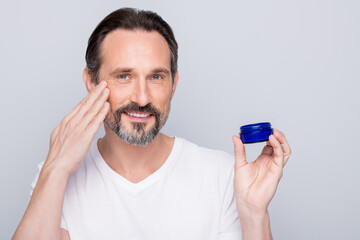 Closeup photo of mature macho guy holding new night cream applying cheek skin metrosexual want get...