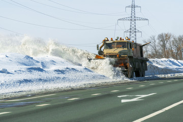 Snowplow cleans the highway from snow on a frosty day