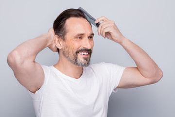 Closeup photo of macho cheerful mature guy holding new hairbrush try quality of product on himself...