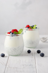 Chia seed pudding with fresh berries on a white wooden table.