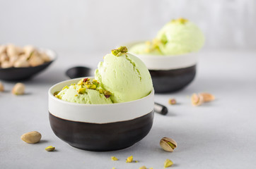 Pistachio ice cream in a bowls on a gray concrete background.