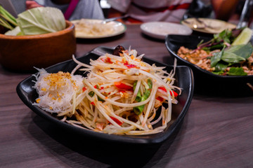 Spicy papaya salad in black plate.