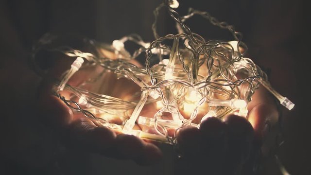 glowing string light garland in woman hands closeup
