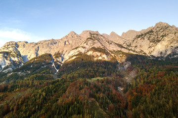 Naklejka premium Aerial view of majestic european Alps mountains covered in evergreen pine forest in autumn.