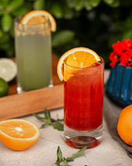 a glass of red juice garnished with orange slice