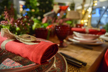 Christmas decoration with coloured crockery, black and silver cutlery, red glasses and table centerpiece