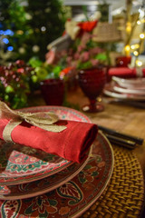 Christmas decoration with coloured crockery, black and silver cutlery, red glasses and table centerpiece