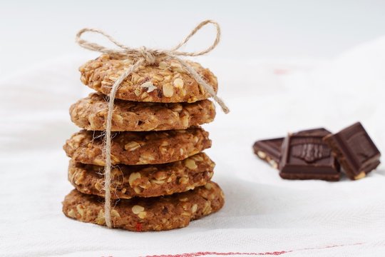 : oatmeal cookies and chocolate on a white towel. White background. Rustic style. High key in food pictures