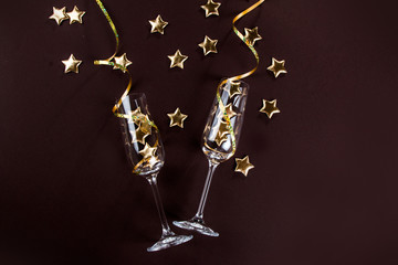 Champagne glasses and star confetti on a dark background top view