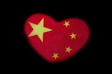 Symbol of love and Chinese patriotism. Heart shape on a red flag with yellow stars. Black background. The concept of a wedding in China or a celebration of Valentine's Day.