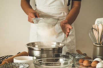 Woman adds some flour to dough on wooden table. Woman hands kneading fresh dough. 