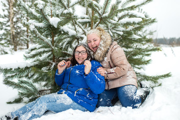 Obraz premium Two adult women fooling and having fun like children in snowy winter day outdoor.