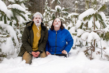 Fototapeta na wymiar Portrait of funny couple with thier faces covered with snow standing on knnes in snowy forest