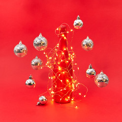 Wine bottle painted red covered garland with lights and flying balls.