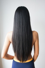 Fototapeta premium Back view of woman with beautiful long straight black hair.