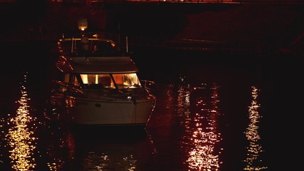Luxurious modern private yacht and boat at the pier at night. Ship crossing skyline in the harbor...