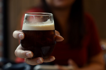 Iced coffee in a holding hand with blurred background.