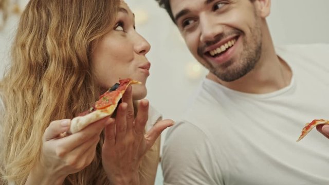 Cropped view of a couple man and woman eating pizza and smiling