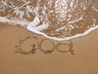 Inscription Goa on the sandy beach and foamy sea water