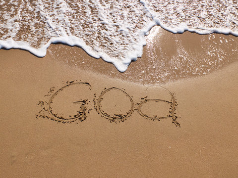 Inscription Goa on the sandy beach and foamy sea water