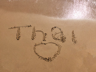Inscription Thai on the sandy beach and foamy sea water