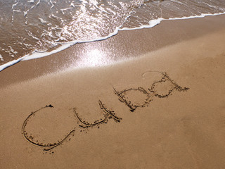 Inscription Cuba on the sandy beach and foamy sea water