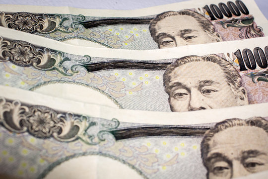 Close up of Japanese 10000 yen banknotes on table. The image is focused on Yukichi Fukuzawa and his eyes on notes.